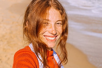 Smiling Woman with Freckles Standing by the Beach